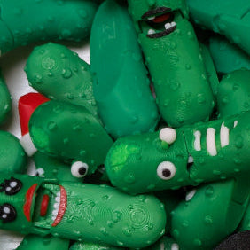 Collection of green toy pickle figures with various facial expressions on a white background